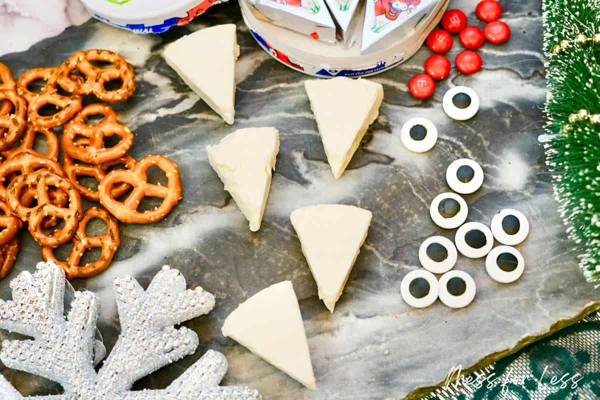 laughing cow cheese unwrapped with pretzels, M&Ms and candy eyes in background