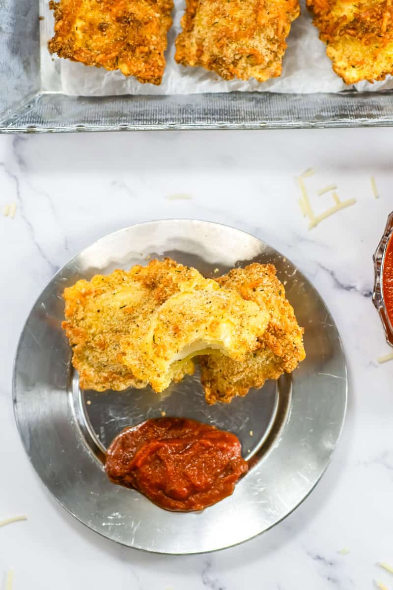 Savor the crispy delight of air fryer ravioli, perfectly presented on a silver plate with a side of rich marinara sauce.