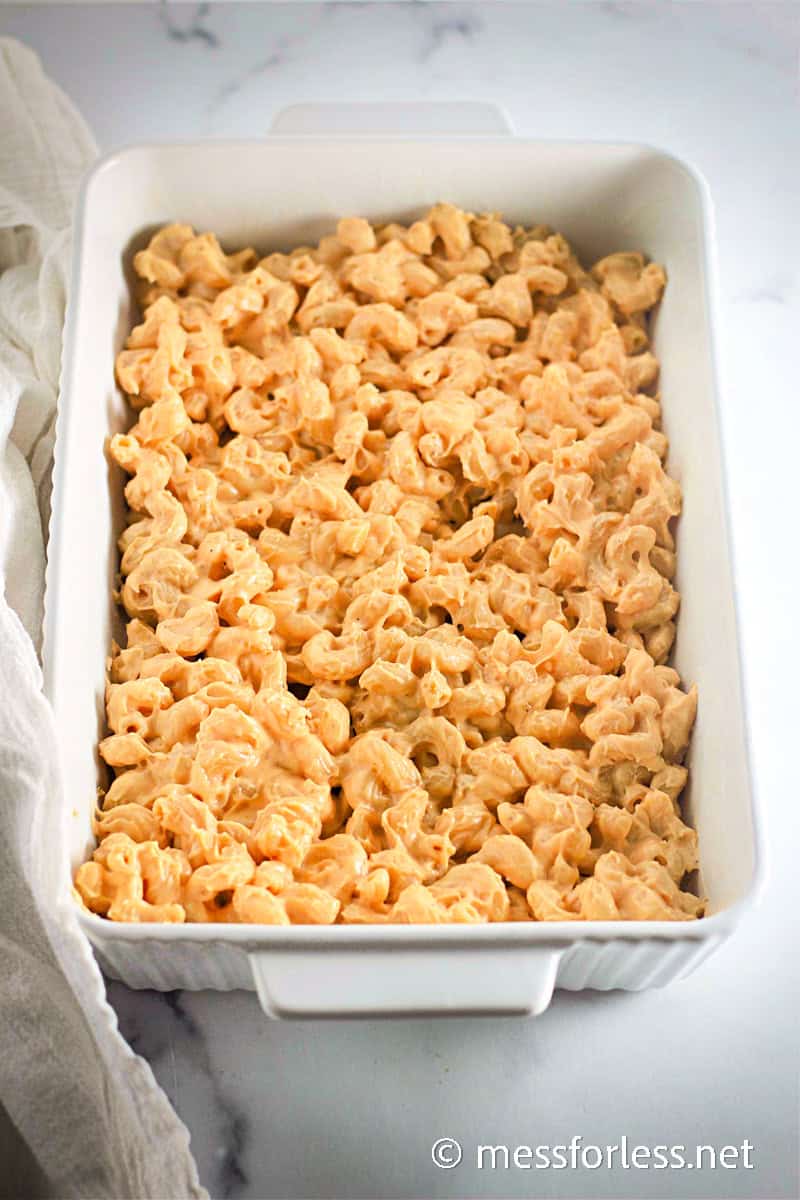 Overhead view of creamy macaroni and cheese in a white baking dish, ready to be topped and baked.