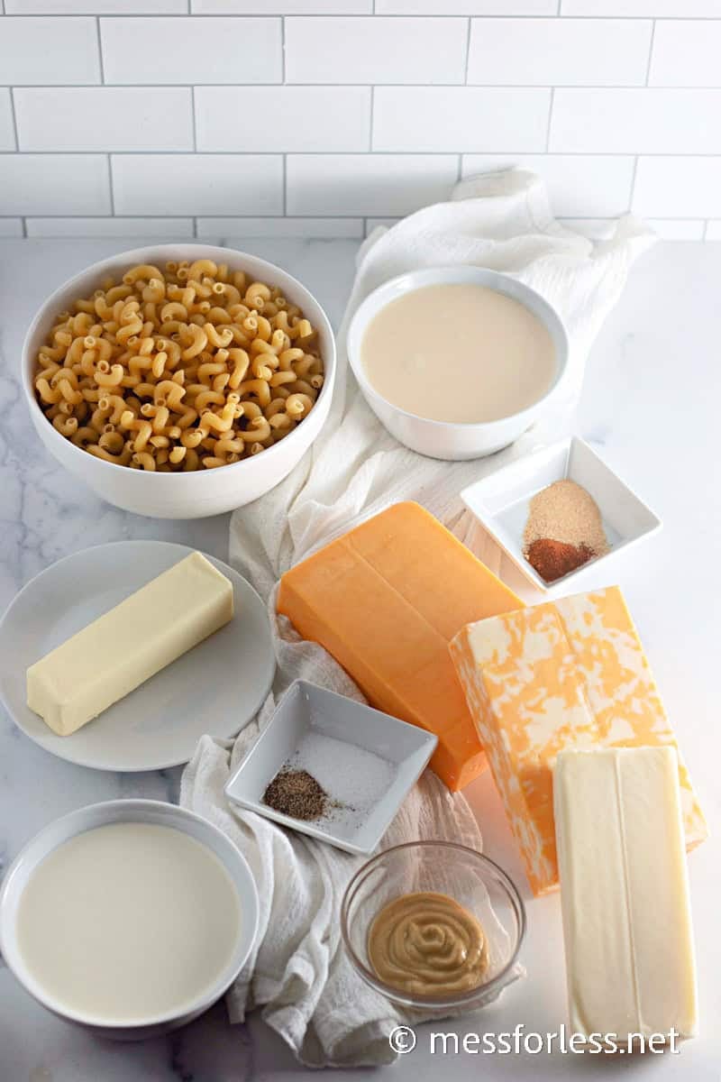 Ingredients for baked macaroni and cheese, including pasta, butter, milk, cheddar, and seasonings.