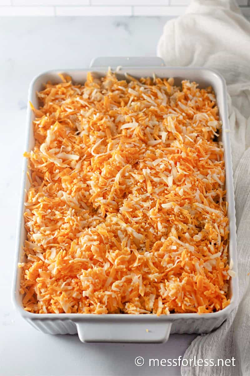 Mac and cheese topped with a thick layer of shredded cheese, ready to go into the oven for baking.