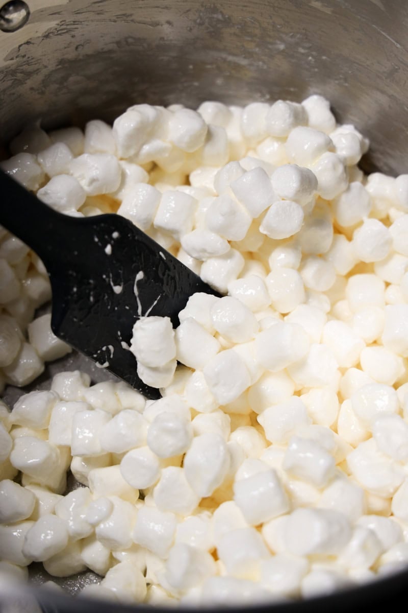 Mini marshmallows in the process of melting inside a saucepan with a spatula