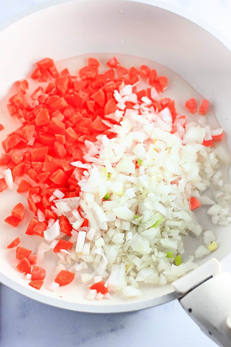 chopped carrots and onions in a white pan
