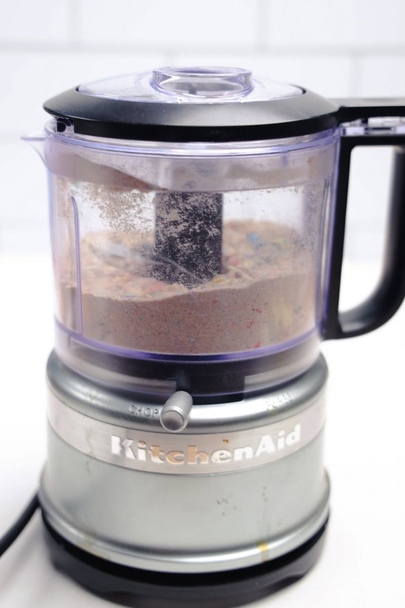 A KitchenAid food processor whirls vibrantly, crafting a Robins Egg Easter Dip with colorful ingredients shimmering in its transparent container.