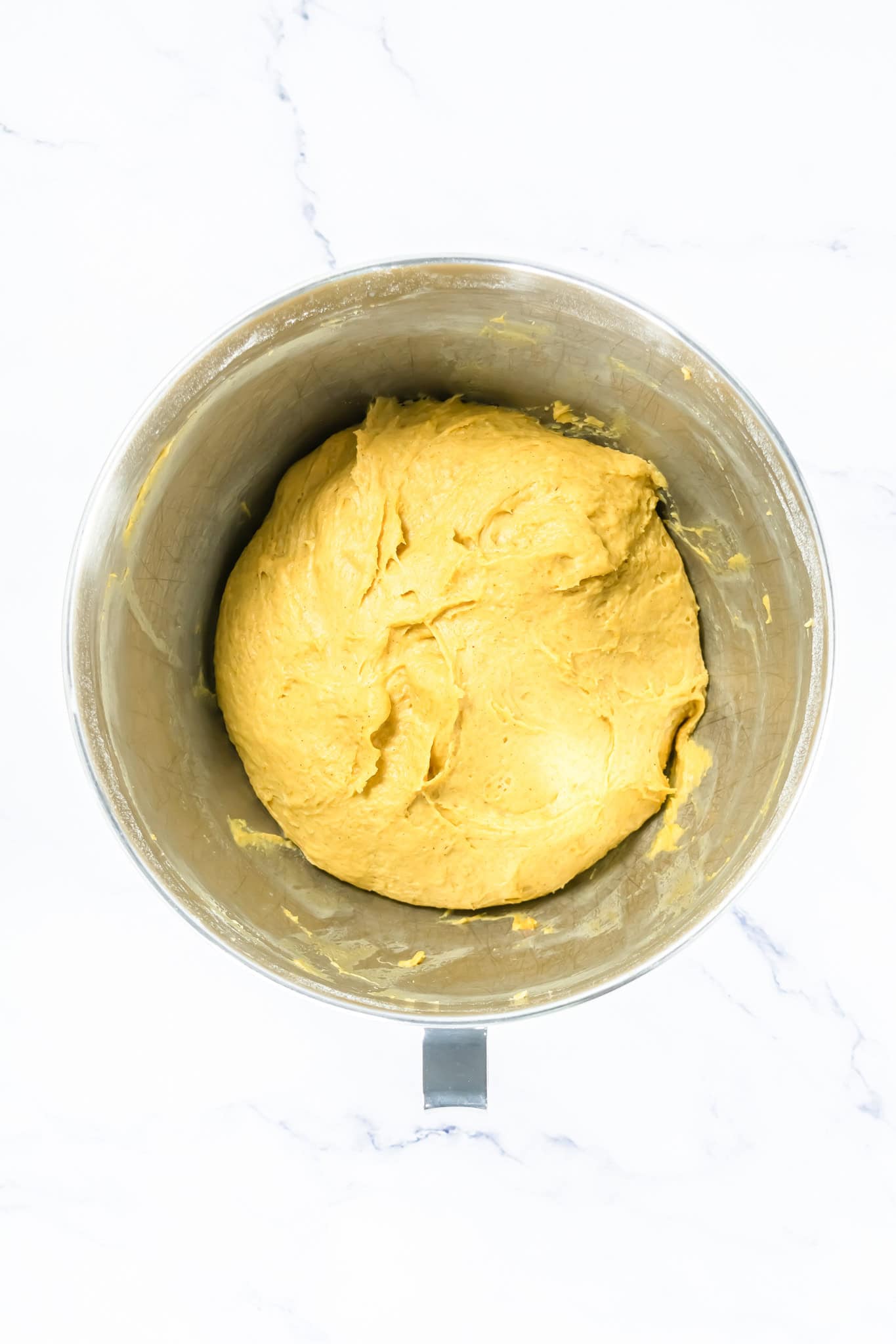 Creamy yellow dough in a metal mixing bowl, ready for baking or cooking. 