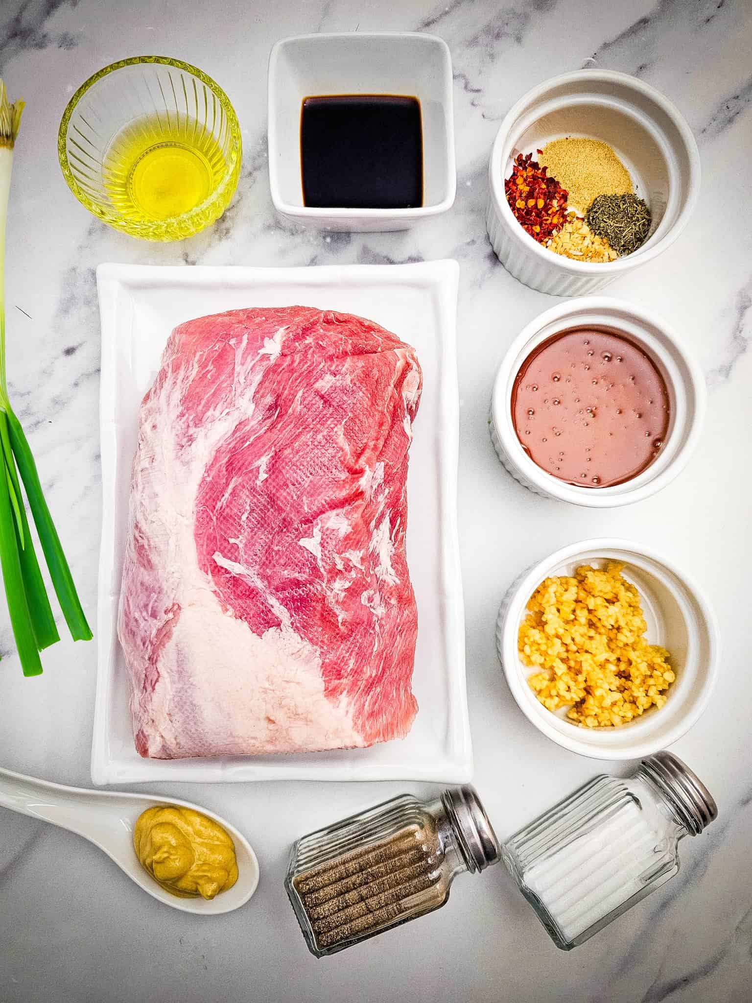Raw Honey Garlic Pork Roast on a plate surrounded by seasonings, mustard, oil, soy sauce, garlic, and green onions—perfect for a flavorful crockpot pork roast.