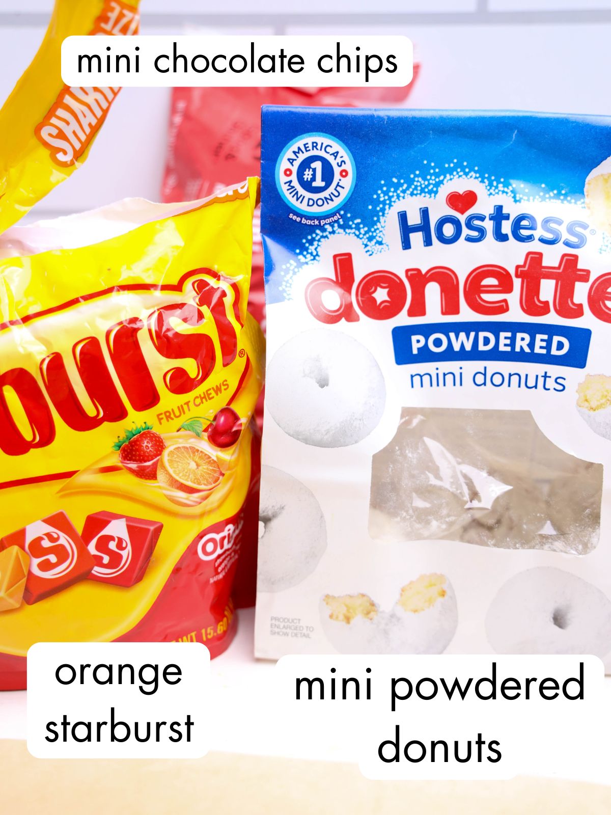 A bag of orange Starburst and a box of Hostess mini powdered donuts on a white surface, perfect for creating a fun Donut Snowman or an easy snowman dessert.