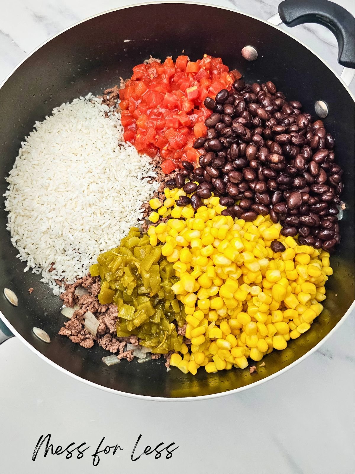 A skillet with ground beef, rice, diced tomatoes, black beans, corn, and green chiles-everything you need to whip up a hearty Taco Rice Casserole. Ready to be mixed and baked for a delicious meal.