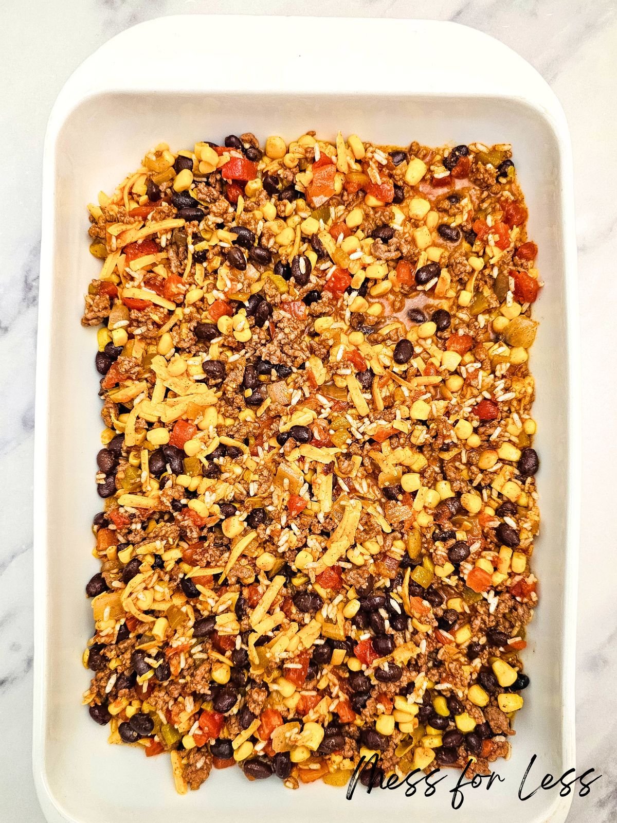 A Taco Rice Casserole dish filled with layered taco ingredients like beans, corn, cheese, and ground meat.