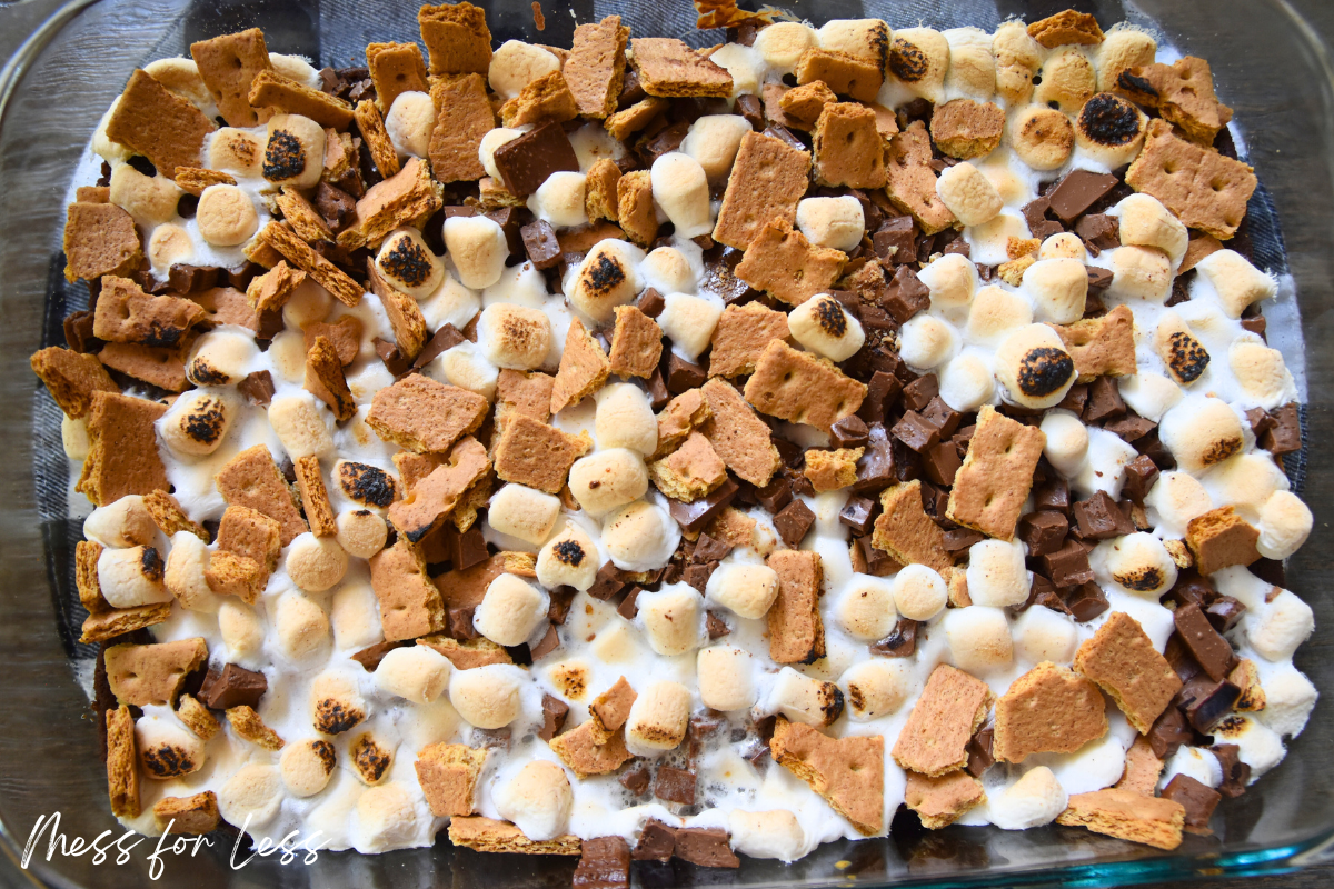 Smores casserole with toasted marshmallows, chocolate chunks, and graham cracker pieces in a glass dish—just like a classic S’mores Brownies Recipe made easy with Boxed Brownie Mix.