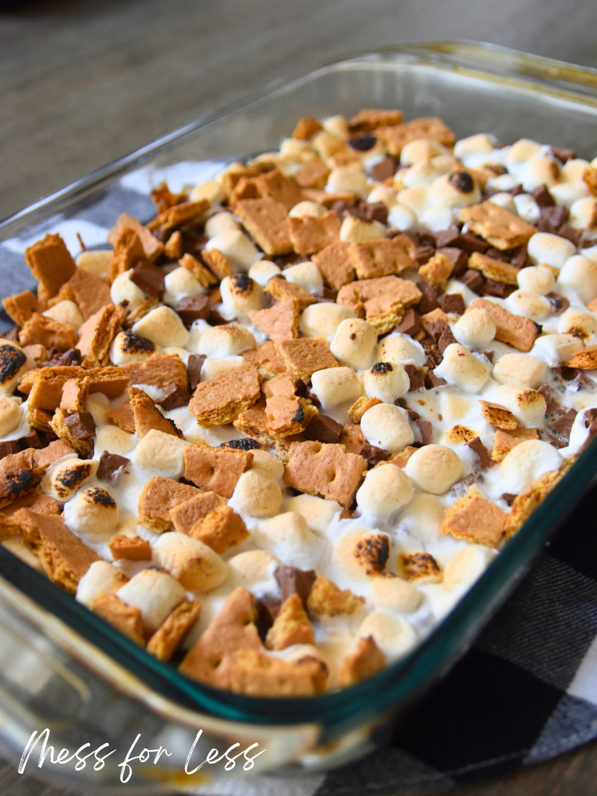 A glass baking dish filled with S’mores brownies, topped with toasted marshmallows and graham cracker pieces, made easy with boxed brownie mix.