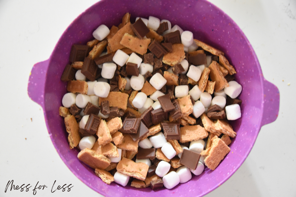 A purple bowl filled with mini marshmallows, chocolate pieces, and broken graham crackers—perfect toppings for your next S’mores Brownies or to elevate a classic boxed brownie mix.